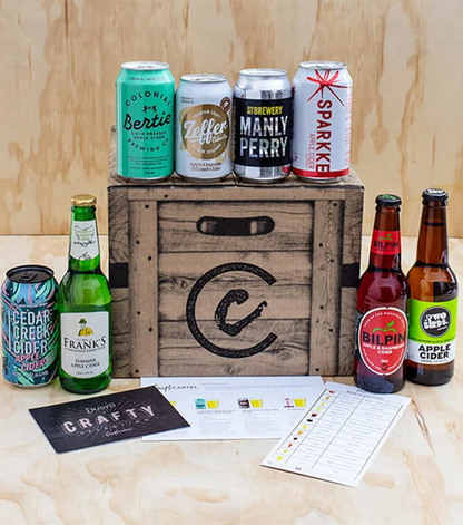 Collection of beer and cider bottles and cans on a wooden crate with a 'Crafty' label.